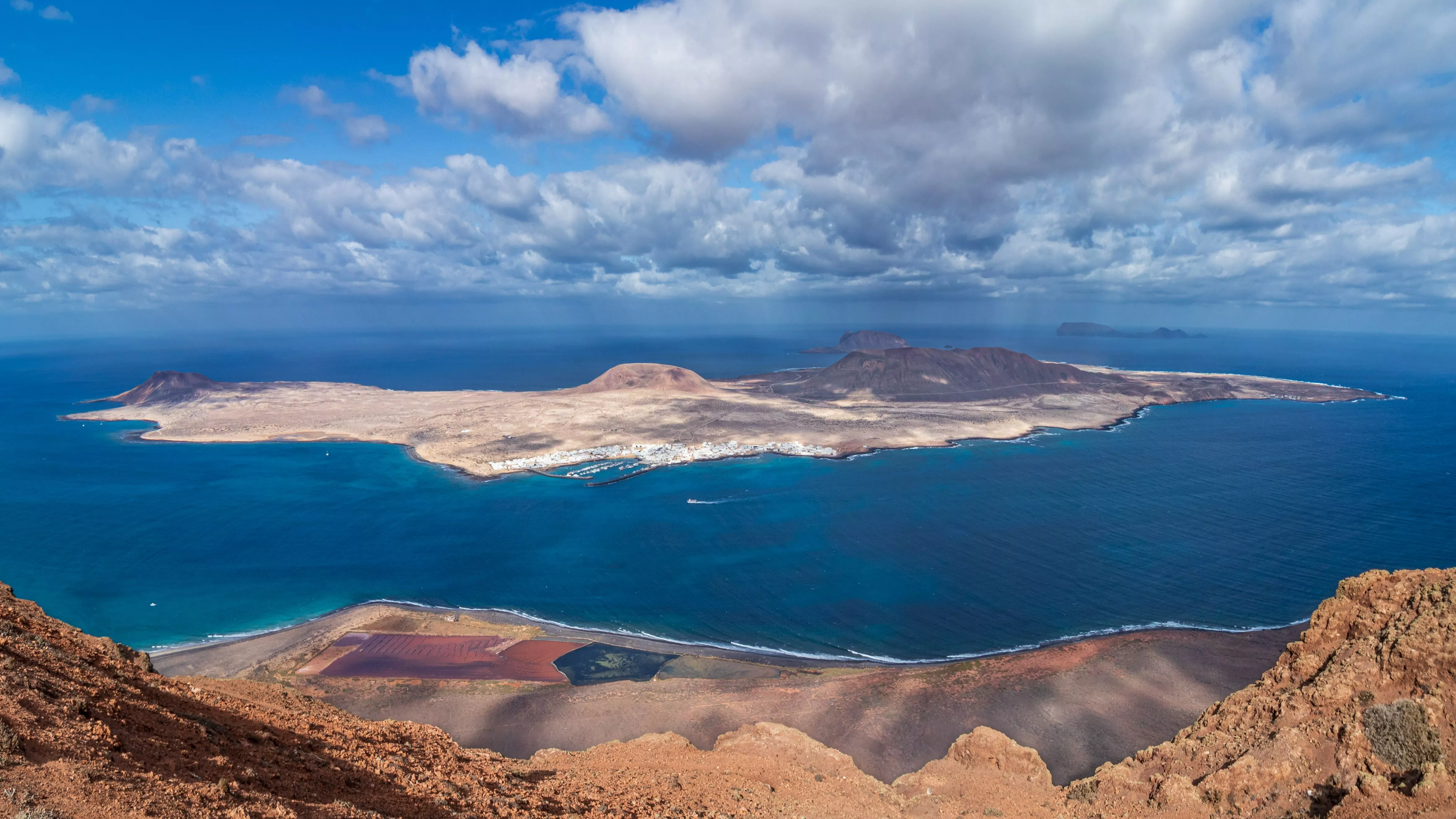 Uitzicht op het rustige eiland La Graciosa met vulkanisch landschap, witte huisjes en helderblauw water vanaf Lanzarote.